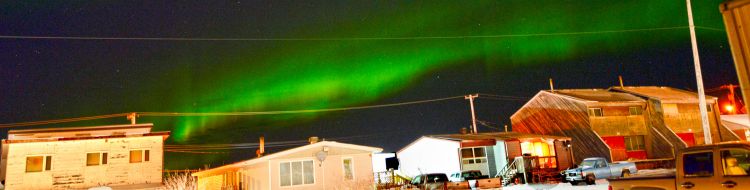 Aurora waves over old buildings in churchill.